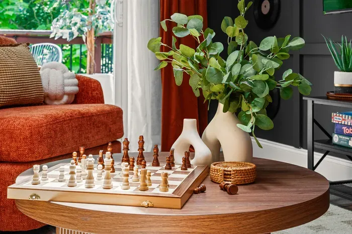 Cozy designer living room with chess table, greenery, and balcony light
