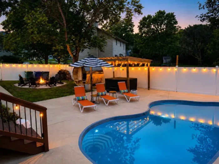 Private backyard oasis with pool, hot tub, fire pit, and evening lights