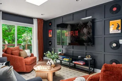 Cozy media lounge with large TV, bold design, and lush natural light