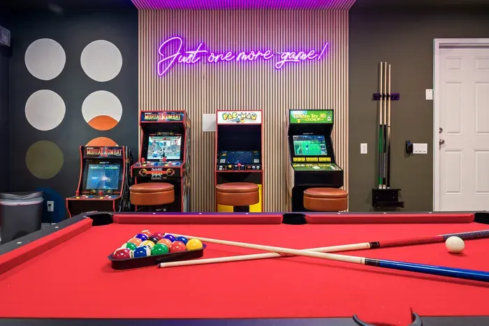 Retro arcade room with neon lights and a full-size pool table