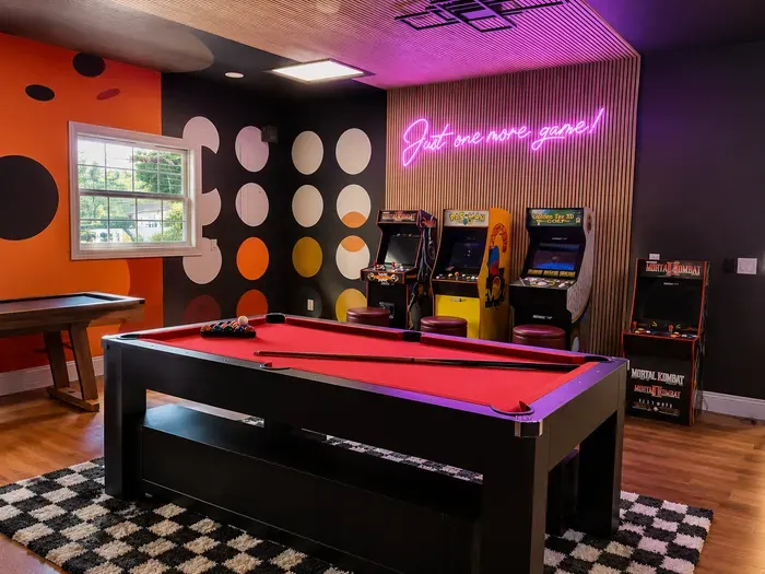 Retro game room with pool table, arcade machines, and neon-lit vibes