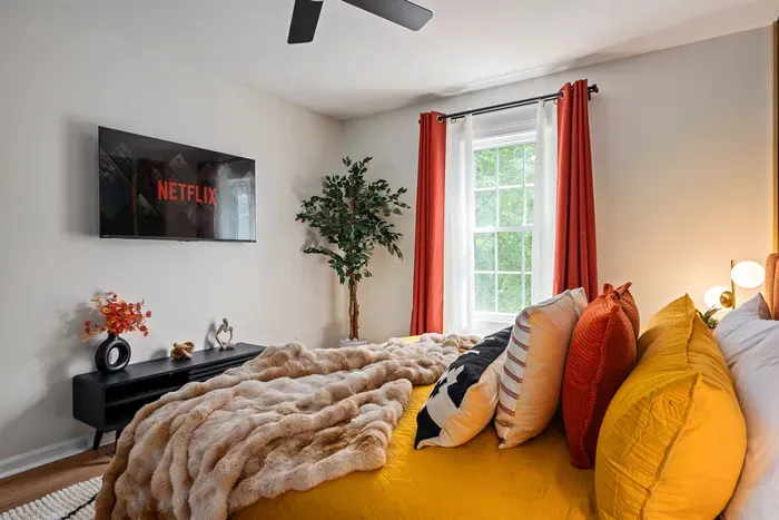 Cozy bedroom with plush bedding, smart TV, and bright natural light