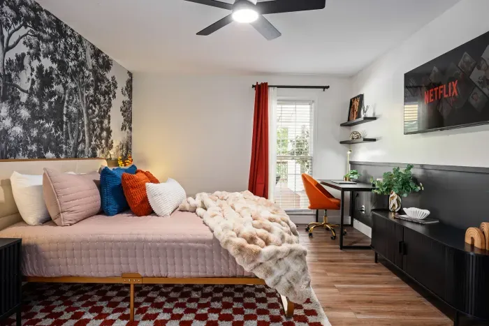 Stylish bedroom with workspace, TV, and cozy designer touches