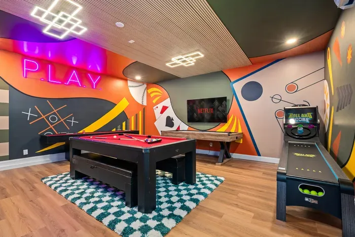 Stylish game room with pool table, arcade hoops, TV, and neon flair