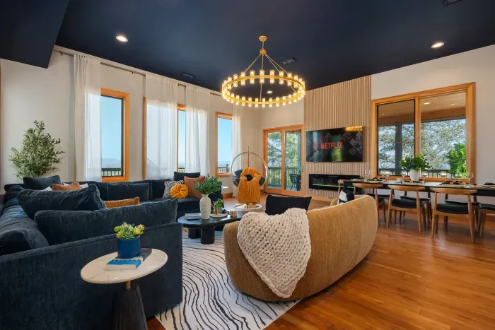 Bright designer living space with large windows, dining area, and TV