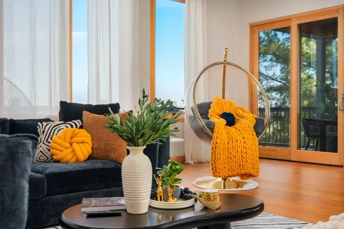 Bright designer living room with hanging chair and serene balcony views