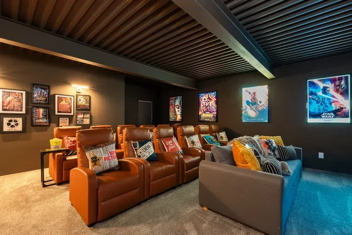 The lower-level theater for the long Saturday night. Sink into the recliners, big screen on, karaoke mics waiting for whoever calls round two after the credits roll.