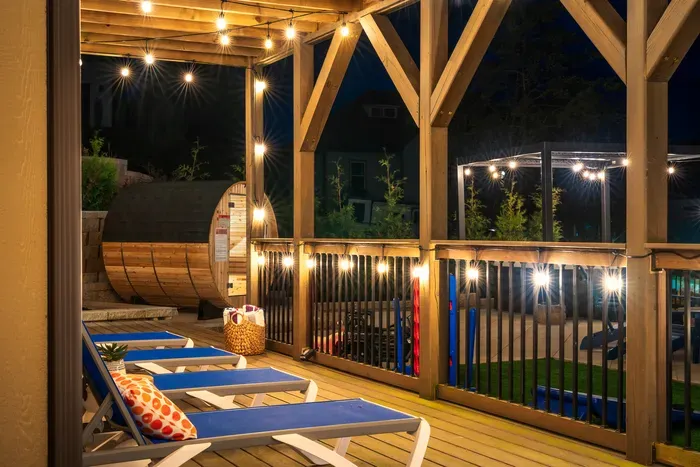 Cozy covered deck with lounge chairs, string lights & a private sauna