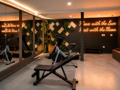 Boutique-style fitness room with cardio equipment, mirrors, and warm lighting