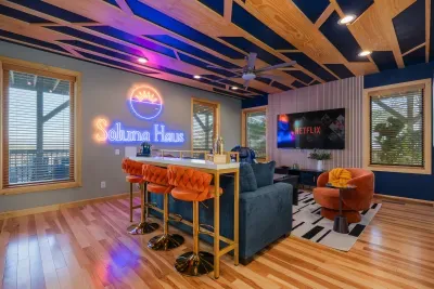The upstairs lounge where friends back from a trail end up before they mean to. TV on low, kitchenette right there, the second living room of the house in full swing.