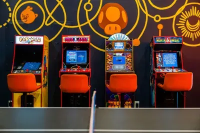 The arcade lineup along the wall, stools waiting, the kid already plotting how they defend the high score for the rest of the trip. Quarter-free and ready to run all week.
