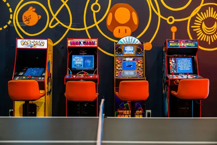 The arcade lineup along the wall, stools waiting, the kid already plotting how they defend the high score for the rest of the trip. Quarter-free and ready to run all week.