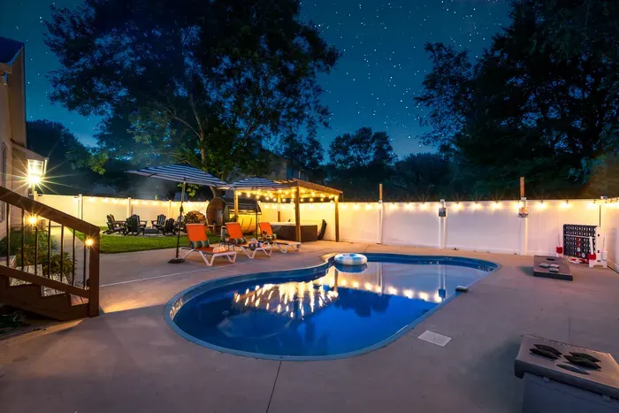 Private lit pool oasis with lounge space, games, and cozy evening ambiance