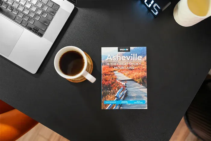 Stylish workspace with coffee and Asheville travel guide