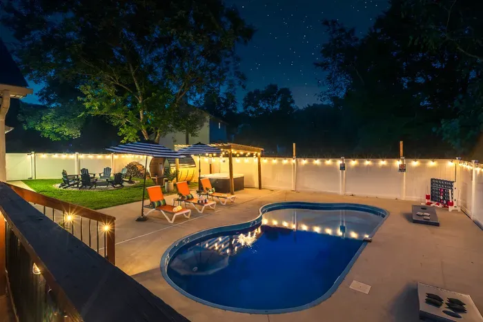 Private pool retreat with string lights, lounge seating, and fun yard games