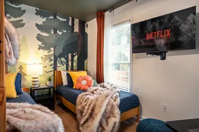 Cozy twin room with woodland mural, streaming TV, and warm designer touches