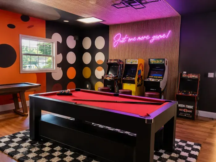 Retro game room with pool table, arcade machines, and neon-lit fun