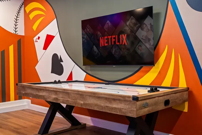 Fun game room with air hockey, bold mural, and big-screen TV
