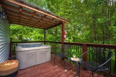 Covered deck with private hot tub nestled in a peaceful wooded setting
