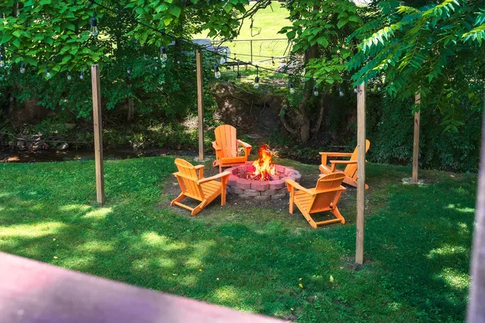 Private backyard fire pit with Adirondack chairs and string lights
