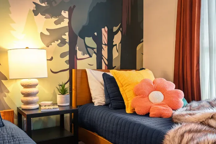 Cozy, colorful bedroom with forest mural and warm designer touches