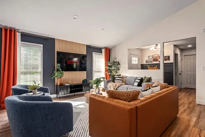 Stylish, sunlit living room with cozy seating and a large smart TV
