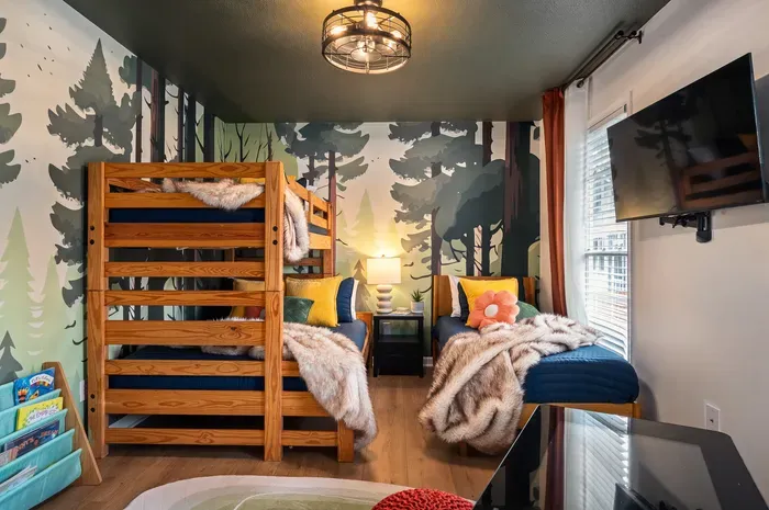 Cozy forest-themed bunk room with TV, natural light, and comfy lounge seating