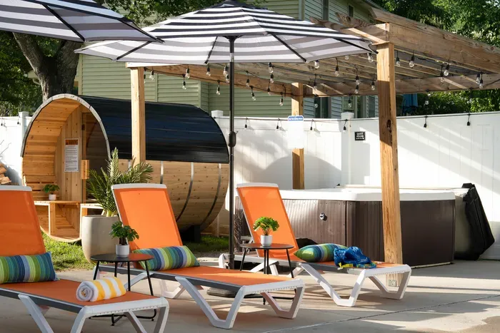Private backyard spa retreat with hot tub, sauna, and sunny loungers