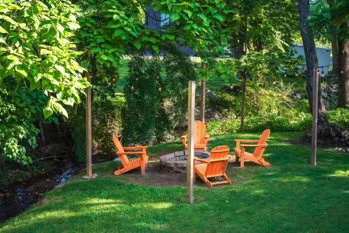 Private wooded fire pit area with Adirondack chairs and lush lawn