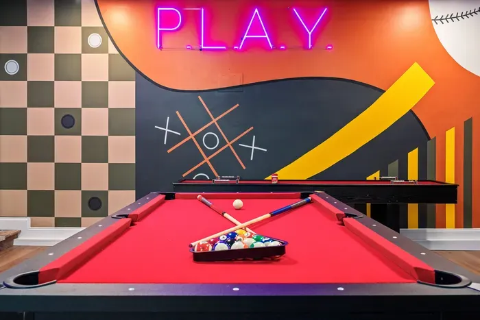 Vibrant game room with neon sign and stylish red-felt pool table