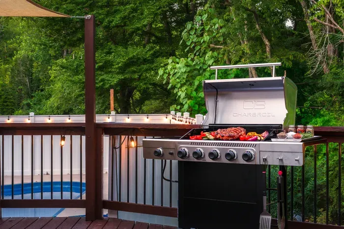 Private backyard deck with grill, string lights, and poolside charm