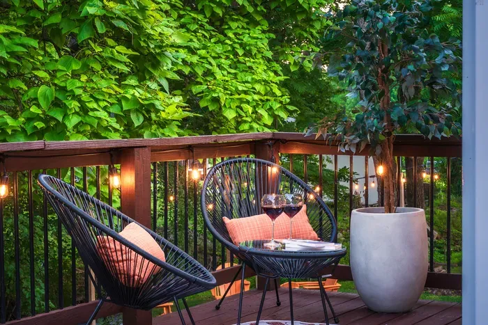 Charming garden-view deck with lounge chairs, wine, and twinkle lights