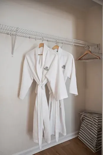 Spacious closet with plush robes, hangers, and handy storage hamper