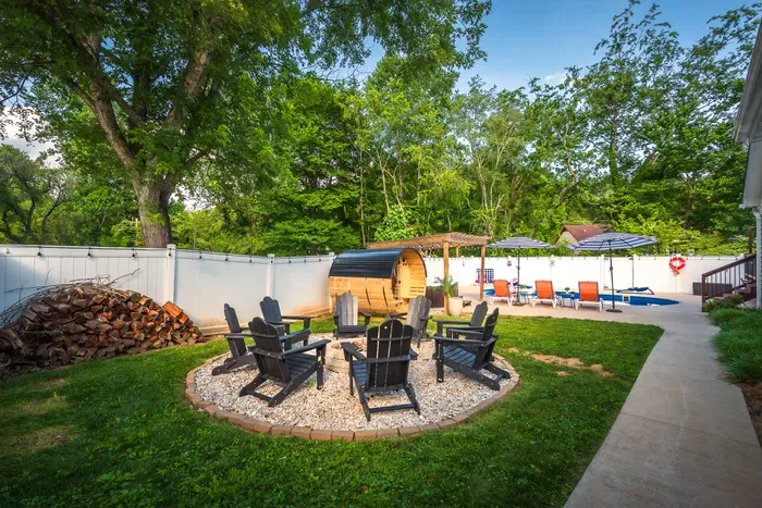 Private backyard oasis with fire pit, sauna, loungers, and fenced yard