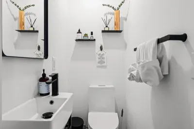 A modern powder room conveniently located on the main level—featuring bold tile, matte black fixtures, and thoughtful details to keep things feeling fresh and functional during your stay.