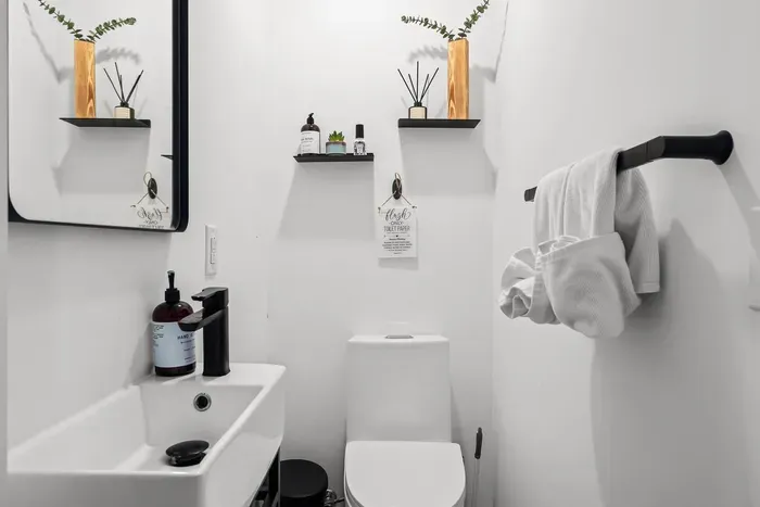 A modern powder room conveniently located on the main level—featuring bold tile, matte black fixtures, and thoughtful details to keep things feeling fresh and functional during your stay.