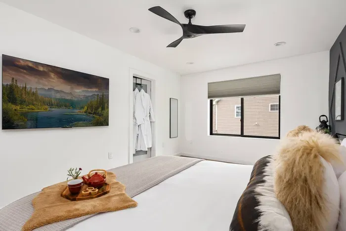 Spacious upstairs primary king suite featuring a large walk-in closet, blackout shades, and ceiling fan. Enjoy a cozy movie night with the in-room smart TV and relax with plush robes for a true luxury retreat.