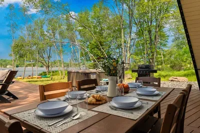 Dine al fresco on the spacious deck with lake views, a large outdoor table, gas grill, and hot tub just steps away for the perfect day-to-night experience.