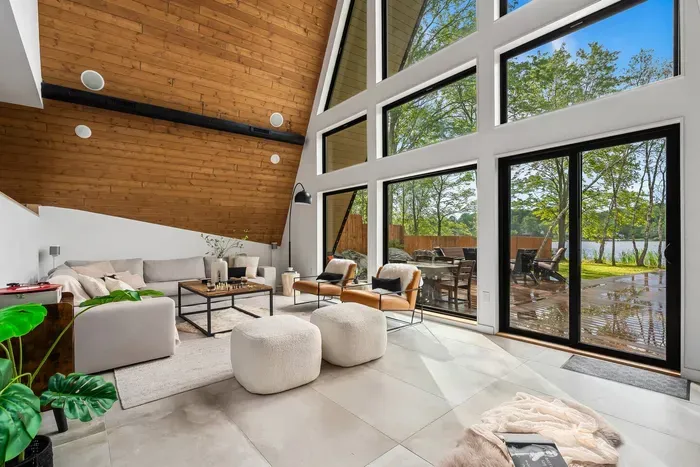 Spacious living room with floor-to-ceiling A-frame windows, stunning lake views, radiant heated floors, Sonos surround sound, and a cozy fireplace.