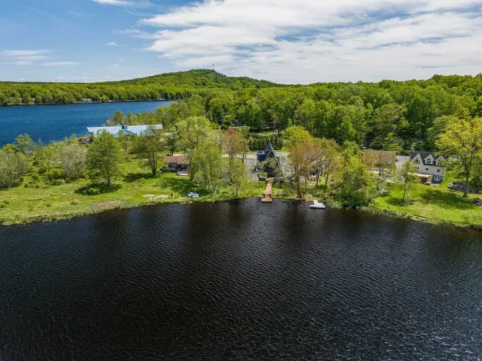 This aerial view captures Moonlit Peak nestled along the peaceful shoreline—offering direct lake access, natural privacy, and postcard-worthy views in every direction.