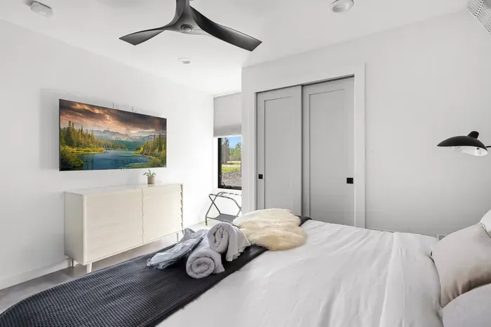 Main floor king bedroom with step-free access. Enjoy heated floors, blackout shades, ceiling fan, and a smart TV for streaming. A peaceful retreat with modern design and luxury linens.