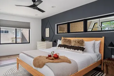 Upstairs primary king bedroom with modern design, blackout shades, and ceiling fan. Features a spacious walk-in closet for added comfort during extended stays.