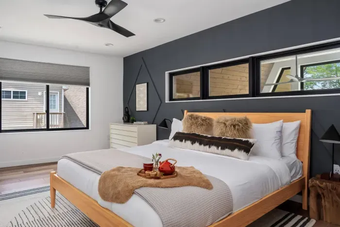 Upstairs primary king bedroom with modern design, blackout shades, and ceiling fan. Features a spacious walk-in closet for added comfort during extended stays.
