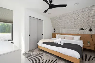 Main floor bedroom with step-free access, heated floors, and a king-size bed dressed in luxury linens. Designed for comfort with blackout shades and a ceiling fan.