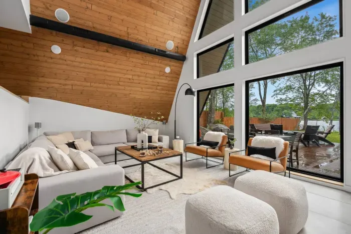 Unwind in a sunlit living room framed by floor-to-ceiling windows — where modern design meets cozy comfort and every seat comes with a lake view.
