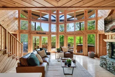 Relax in a sunlit living room with cozy sofa and stone fireplace.