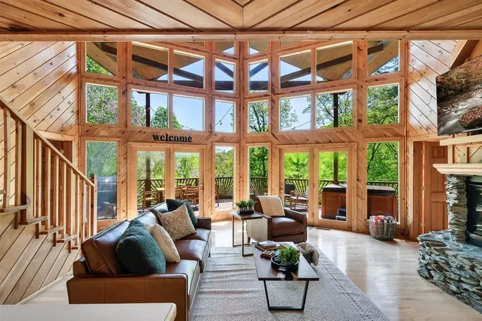 Relax in a sunlit living room with cozy sofa and stone fireplace.
