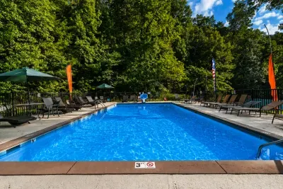 Spacious resort-style swimming pool with comfortable seating, umbrellas, and peaceful mountain views.