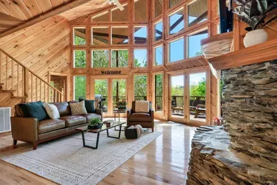 Bright and airy living room with cozy seating and a stone fireplace.