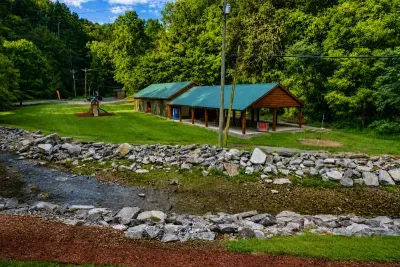 Scenic creekside recreation area with open green space, picnic pavilion, and playground nearby.